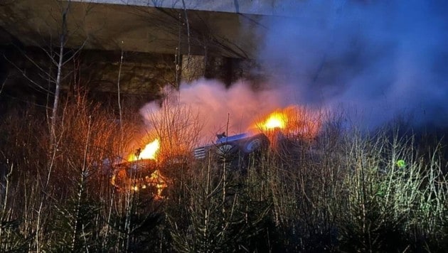 Feuer gefangen hat der Kran-Lkw, der bei Villach von einer Autobahnbrücke gestürzt ist. (Bild: BFKDO-Villach Stadt)