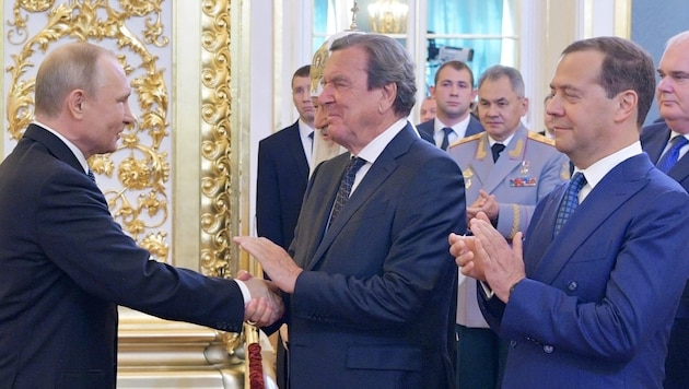 Schröder gratulál Putyinnak 2018-as elnöki beiktatásához, mellette Dmitrij Medvegyev tapsol, a háttérben pedig Szergej Sojgu védelmi miniszter egyenruhában. (Bild: APA/AFP/SPUTNIK/Alexey DRUZHININ)
