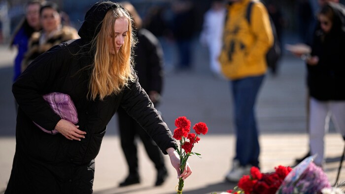 Eine Frau legt vor der Crocus City Hall Blumen nieder.