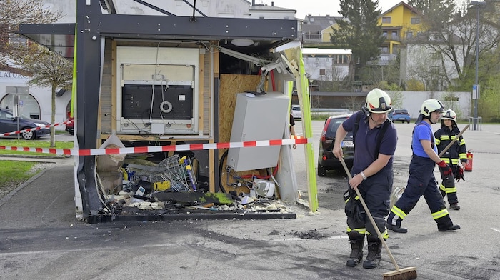Einsatzkräfte beim Aufräumen vor dem demolierten Selbstbedienungsladen in Mattighofen