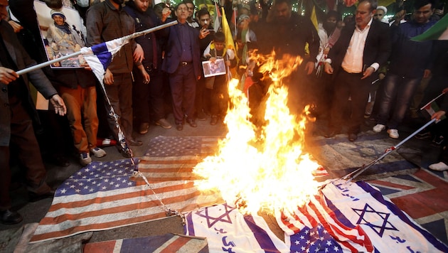 Angry Iranians burn US and Israeli flags after the airstrike on the Iranian embassy in Syria. (Bild: AFP)