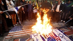 Wütende Iraner verbrennen nach dem Luftschlag auf die iranische Botschaft in Syrien Flaggen der USA und Israels. (Bild: AFP)