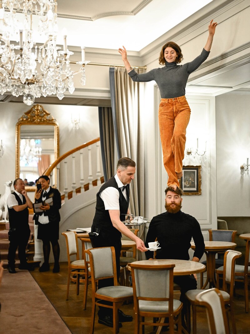 An unusual sight: Christina Zauner balancing on her boyfriend Sam's head while Mr. Dragan calmly serves a cappuccino in the café in Bad Ischl. (Bild: Markus Wenzel)