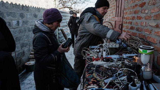 Ukrayna'da insanlar elektronik cihazlarını şarj ediyor. (Bild: AFP)