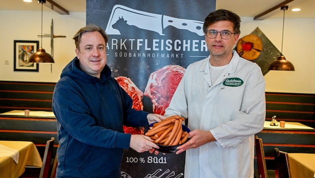 Philipp Kaufmann mit Josef Fischelmaier (r.) und der neuen Linzer Wurst, die es ab 30. April in der neuen Marktfleischerei am Linzer Südbahnhofmarkt zu kaufen gibt. (Bild: Dostal Harald)