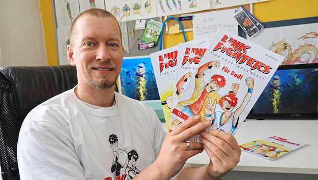 Bernd Trübswasser mit den ersten drei Heften von „Link Fighters“ in seinem Büro. (Bild: Christian Jauschowetz)