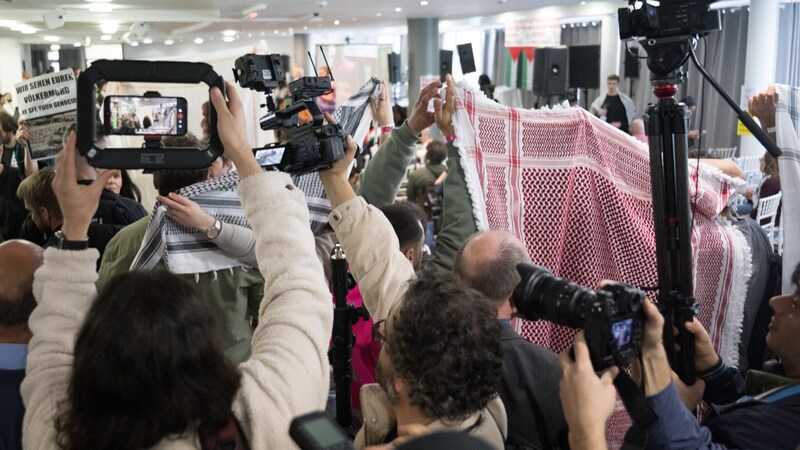 Filistin Kongresi 2024 başlamadan önce katılımcılar takke ve eşarplarla gazetecilerin çekim yapmasını ve fotoğraf çekmesini engellemeye çalıştı. (Bild: APA/dpa/Sebastian Gollnow)