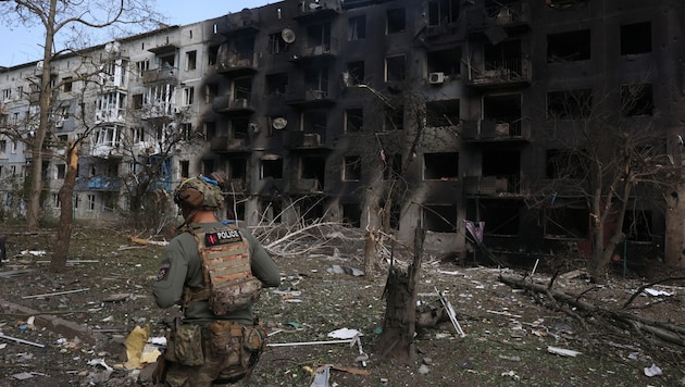 Ein ukrainischer Polizist geht nach russischen Luftangriffen an einem zerbombten Wohnhaus vorbei. (Bild: APA/AFP/Anatolii STEPANOV)