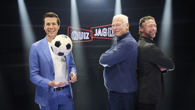 Presenter Florian Lettner (left with the original Cordoba ball from 1987) invites viewers to the "Quizjagd" country match in the run-up to Euro 2024. Toni Polster (center) for Austria will compete against Steffen Freund for Germany. (Bild: ServusTV/Philipp Carl Riedl)