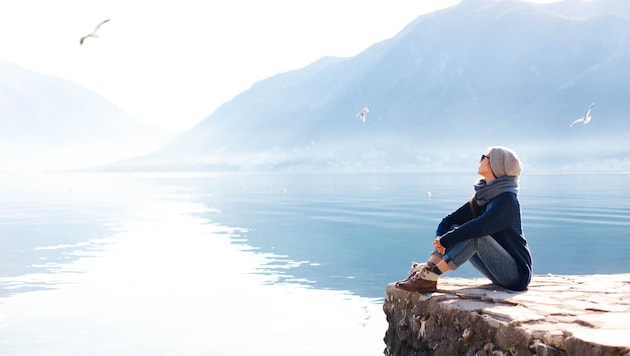 A woman by a lake (Bild: stock.adobe.com – Marina April)