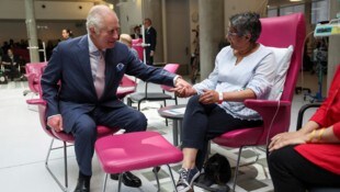 König Charles hält einer Krebspatientin die Hand.