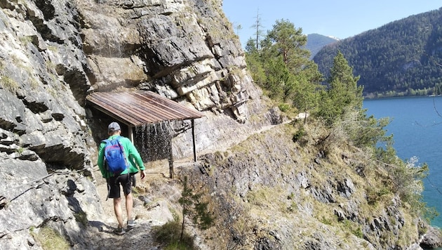 Der Steig führt in den Felsen über dem See dahin, das Dach schützt uns vor einem lieblichen Wasserfall. (Bild: Peter Freiberger)