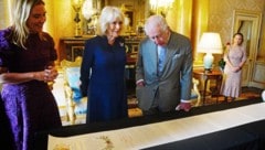 Charles und Camilla staunen über die Krönungsrolle. (Bild: APA/AFP/POOL/Victoria Jones)