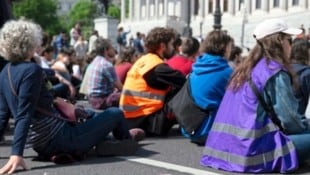 Die Aktivisten klebten sich Samstagvormittag vor das Parlament und blockierten damit den Verkehr. (Bild: REUTERS)