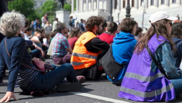 Die Aktivisten klebten sich Samstagvormittag vor das Parlament und blockierten damit den Verkehr. (Bild: REUTERS)