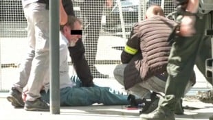 Sicherheitskräfte fixieren den Täter am Tatort auf dem Boden. (Bild: Krone KREATIV/AFP/RTVS)