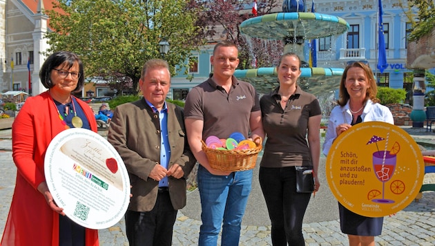 Bürgermeister Franz Mold, Vizebürgermeister Andrea Wiesmüller und Wirtschaftsstadträtin Anne Blauensteiner überreichten dem Wirtepaar des Stadtcafés Juwel Julia und Stefan Fidi-Weißenhofer beim Hundertwasserbrunnen im Zentrum von Zwettl die Mega-Bierdeckel. (Bild: Stadtgemeinde Zwettl)