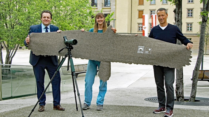 Landesrat René Zumtobel, Elisabeth Weninger und der GF des Naturparks Ötztal, Thomas Schmarda (v.li.), halten die Silhouette eines Bartgeiers aus Stoff, die die beeindruckende Flügelspannweite der Greifvögel erfahrbar macht.