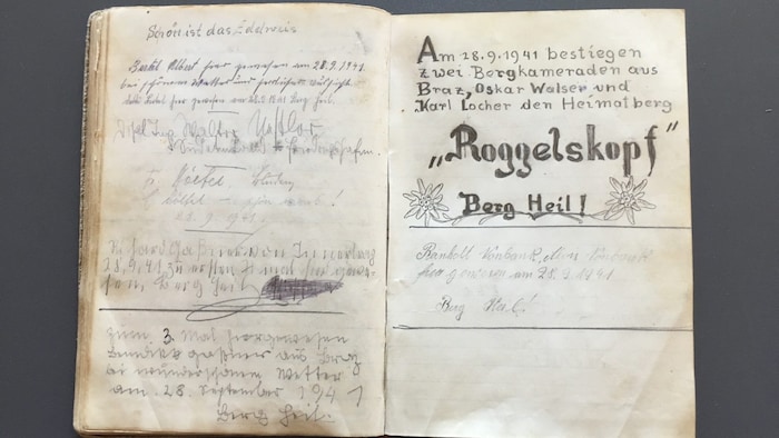 Zwei Alpinisten tragen sich im Gipfelbuch am Roggelskopf ein.