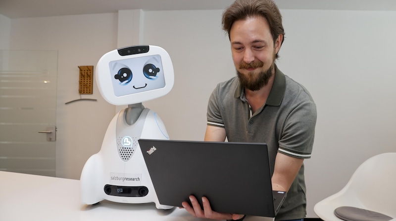 Oliver Jung lets the little robot look over his shoulder while programming. "Buddy" is designed to prevent loneliness and keep old people healthy for longer. (Bild: Tschepp Markus)