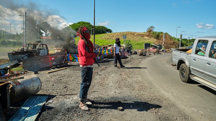 Demonstrators at a road blockade in New Caledonia with flags of the "Kanak and Socialist Front of National Liberation" (FLNKS)