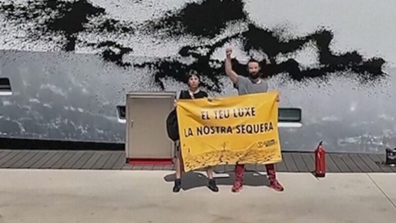 Die Klimaaktivisten entrollten unter anderem ein gelbes Plakat mit der Aufschrift „El teu luxe la nostra sequera“ (Euer Luxus ist unsere Dürre). (Bild: kameraOne (Screenshot))