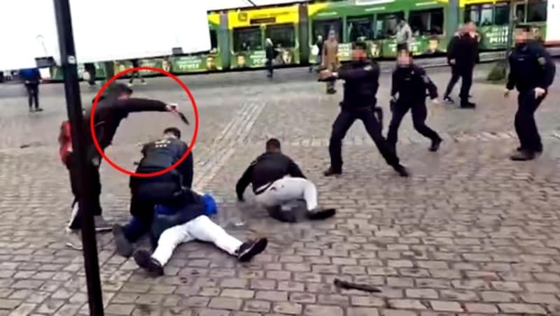 Sulaiman A. uses the combat knife to stab Rouven L., who is holding the man in the blue jacket. He had mistakenly struck a helper (right) who had restrained the assassin. (Bild: Quelle: YouTube/Augen auf!; krone.at)