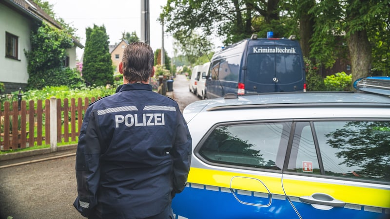 Polizeibeamte stehen an dem Tatort auf der Straße. (Bild: APA/dbgrafie.de/David Breidert)