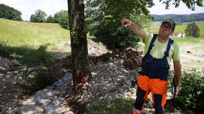 Herbert Weiß zeigt der „Krone“, wie es durch zwei Bäche in Dorfbeuern zu den Überschwemmungen gekommen ist. (Bild: Tröster Andreas)