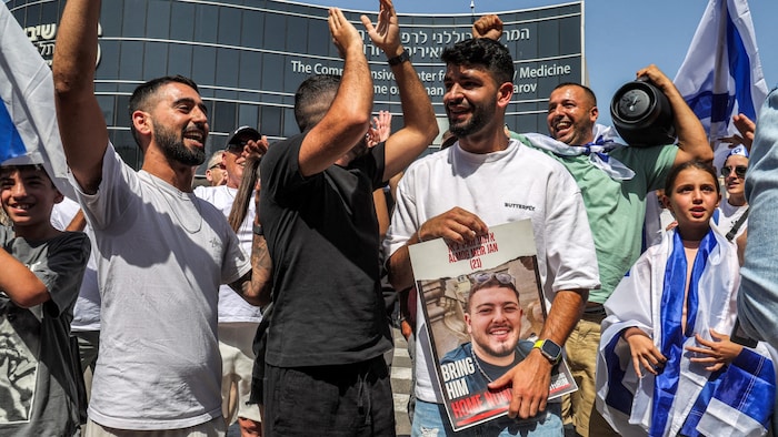 Ein Mann hält ein Bild von Almog Meir Jan, einer der vier befreiten israelischen Geiseln.