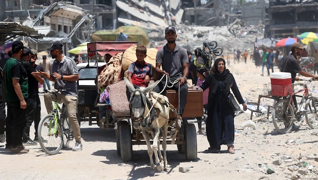 Ein Eselskarren transportiert Haushaltsgegenstände, während er an zerstörten Gebäuden im Flüchtlingslager Jabalia im nördlichen Gazastreifen vorbeifährt. (Bild: APA/AFP/Omar AL-QATTAA)