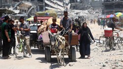 Ein Eselskarren transportiert Haushaltsgegenstände, während er an zerstörten Gebäuden im Flüchtlingslager Jabalia im nördlichen Gazastreifen vorbeifährt. (Bild: APA/AFP/Omar AL-QATTAA)