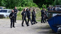 Polizisten suchen auf einem Firmengelände nach der vermissten Schülerin. (Bild: APA/dpa/Robert Michael)