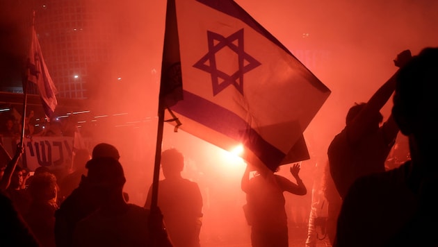 Ein Demonstrant hält eine israelische Flagge während einer Kundgebung Tel Aviv, in deren Rahmen zu einem Geisel-Abkommen aufgerufen wird. (Bild: PA/AFP/JACK GUEZ)