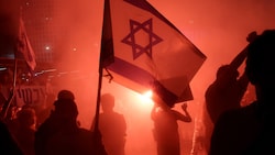 Ein Demonstrant hält eine israelische Flagge während einer Kundgebung Tel Aviv, in deren Rahmen zu einem Geisel-Abkommen aufgerufen wird. (Bild: PA/AFP/JACK GUEZ)