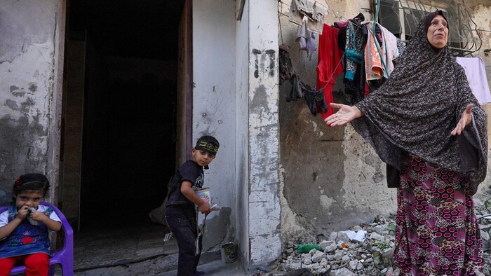 Eine Frau zeigt ihr zerstörtes Haus im Gazastreifen.