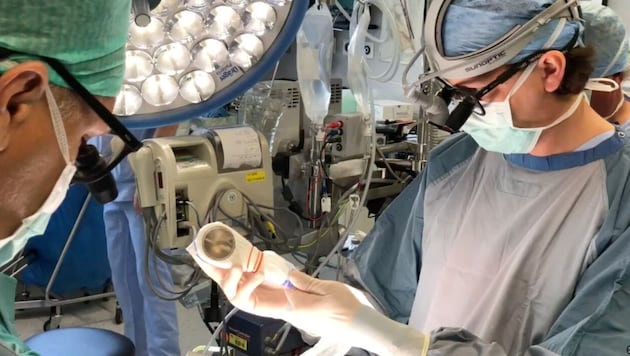 Johannes Holfeld (r) hält das Stoßwellengerät während einer Bypass-Operation in der Hand. (Bild: Univ.-Klinik f. Herzchirurgie/MUI)