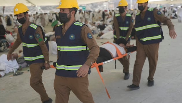 Mentőmunkások elvisznek egy embert, aki a hőségben összeesett a Mekka melletti Mina-völgyben. (Bild: AP ( via APA) Austria Presse Agentur)