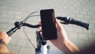 Mit seinem Mobiltelefon in der Hand wurde ein Radfahrer von der Polizei aufgehalten – zahlen muss er aber nicht. (Bild: stock.adobe.com/SFIO CRACHO – stock.adobe.com)