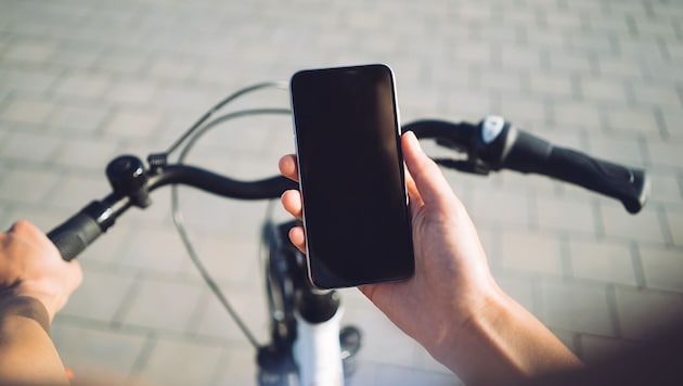 Mit seinem Mobiltelefon in der Hand wurde ein Radfahrer von der Polizei aufgehalten – zahlen muss er aber nicht. (Bild: stock.adobe.com/SFIO CRACHO – stock.adobe.com)