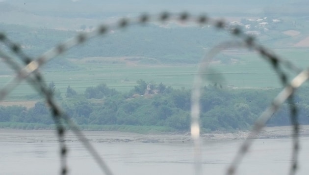 Askerden arındırılmış bölgede Güney Kore'ye ait dikenli tel örgülerin arasından Kuzey Kore'ye ait bir sınır karakolunun görünümü (Bild: Associated Press)