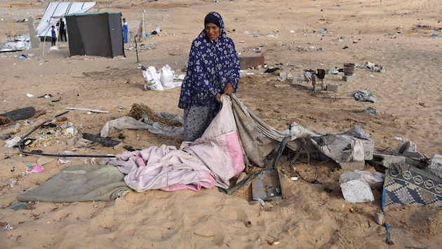 Yerinden edilmiş Filistinli aileler eşyalarını toplarken bir kadın çadırını katlıyor. (Bild: APA/AFP/Bashar TALEB)