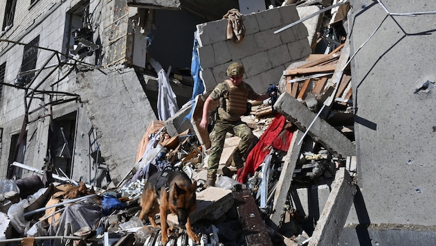 Mentő egy lerombolt ház romjai között Harkivban (Bild: AFP/Sergey Bobok)