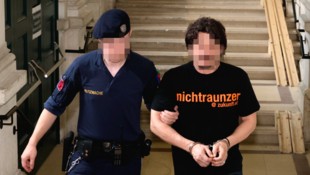 Der Rumäne wird aus der U-Haft vorgeführt. Sein T-Shirt entpuppt sich schnell als Selbstironie. (Bild: Bissuti Kristian/Kristian Bissuti, Krone KREATIV)
