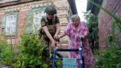 Ein Polizist hilft einer Ukrainerin, in eine sicherere Gegend zu kommen. (Bild: AP/Evgeniy Maloletka)