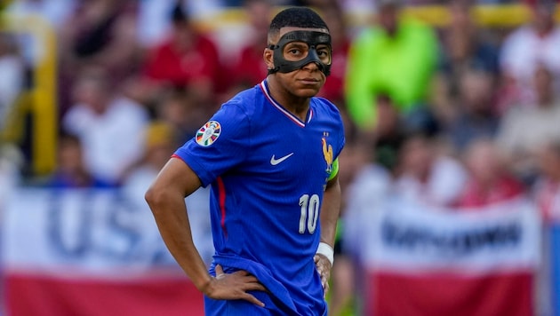Kylian Mbappe can't get to grips with his mask. (Bild: AP ( via APA) Austria Presse Agentur/ASSOCIATED PRESS)