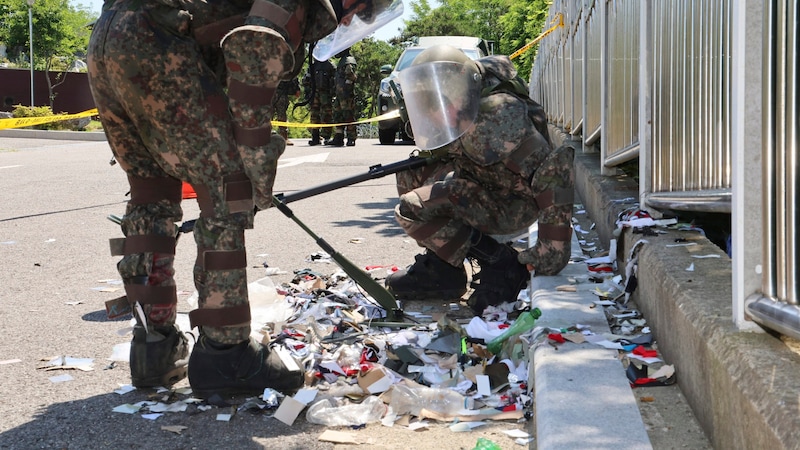In Schutzausrüstung inspiziert das südkoreanische Militär die abgestürzten Mülbeutel. (Bild: AP ( via APA) Austria Presse Agentur/Yonhap/Im Sun-suk)