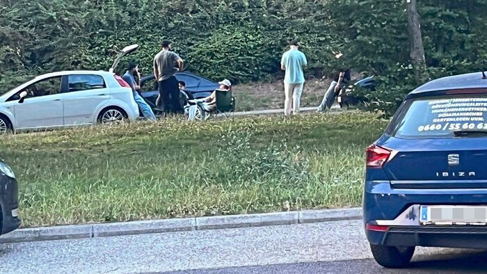 Jugendliche packen ihre Campingstühle am Parkplatz aus.