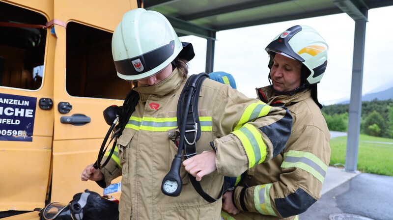 Ausbildungsleiter Gerhard Schöpf hilft Redakteurin Nicole Greiderer beim Anziehen des schweren Atemschutzgeräts. (Bild: Birbaumer Johanna)