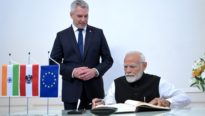 Modi (jobbra) aláírja Nehammer vendégkönyvét a kancellárián. (Bild: APA/ROLAND SCHLAGER)